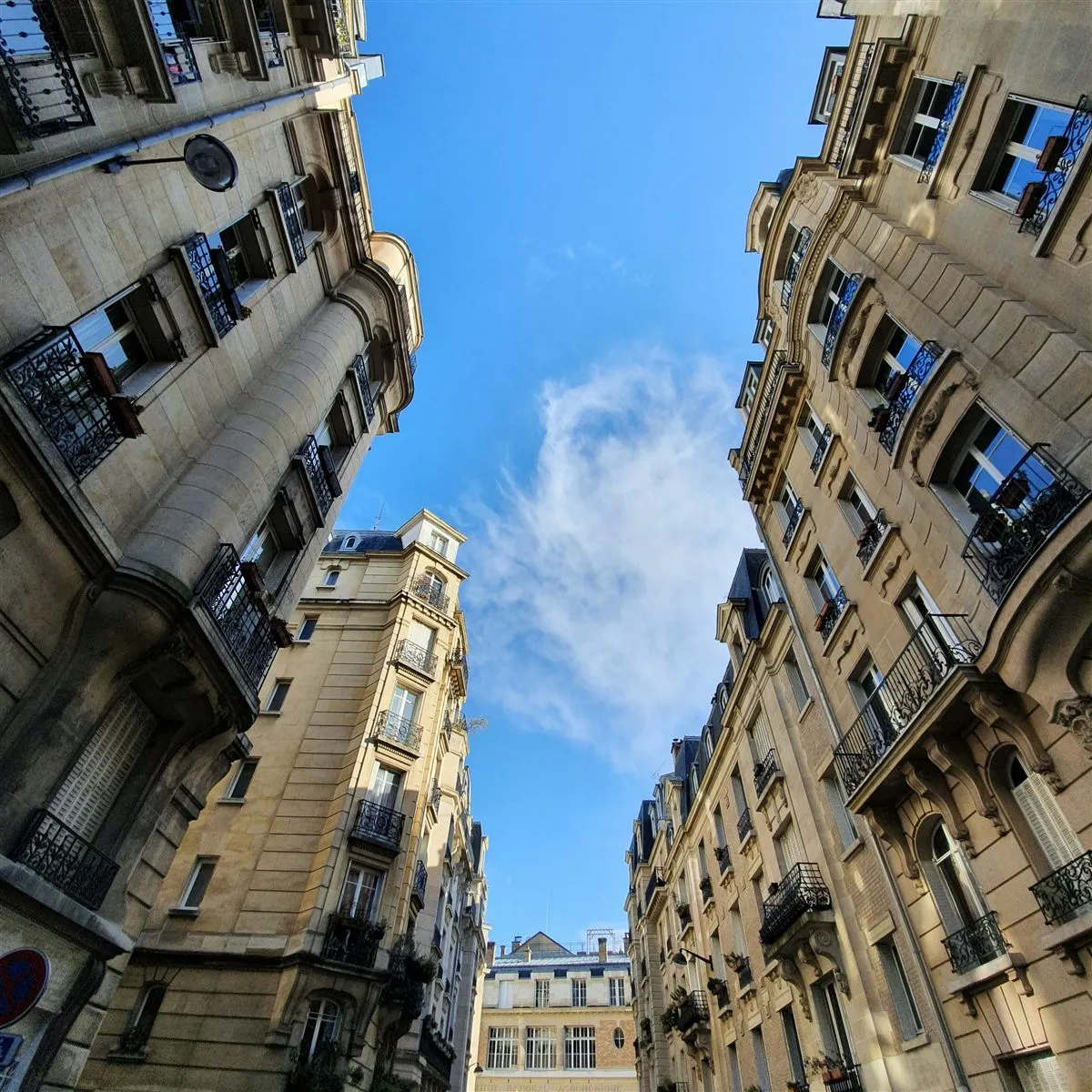 Cour d'immeubles haussmanniens parisiens, vue en contre-plongée vers un ciel bleu